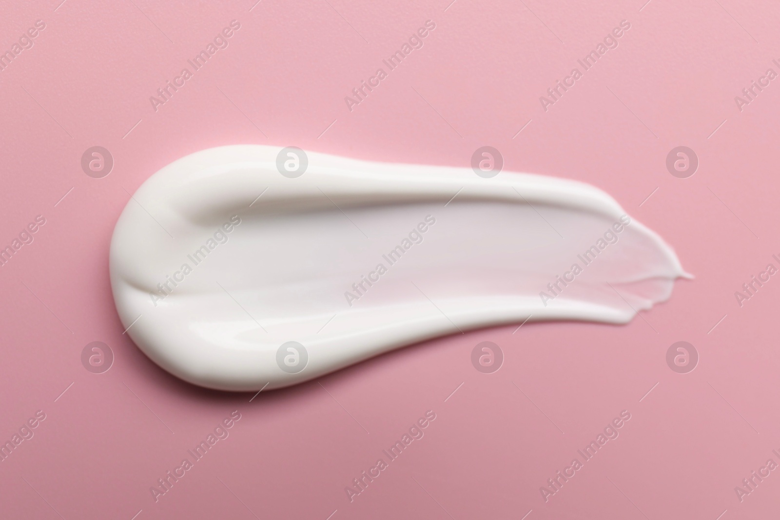 Photo of Cream on pink background, top view. Sample of cosmetic product