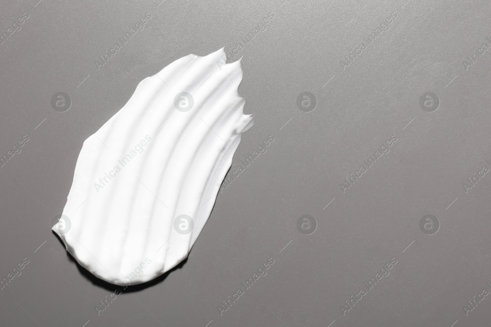 Photo of Cream on grey background, top view and space for text. Sample of cosmetic product