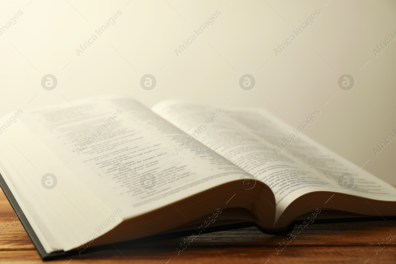 Photo of Open Holy Bible in English language on wooden table, closeup