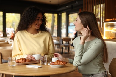 Photo of Happy women with coffee drinks chatting in cafe