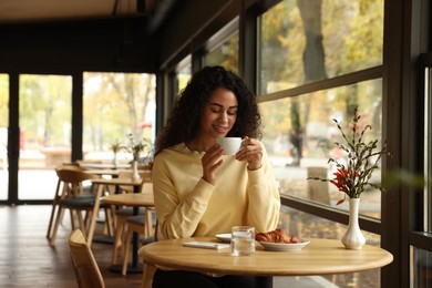 Photo of Woman enjoying her aromatic coffee at table in cafe