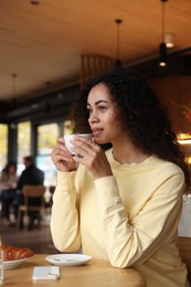 Photo of Woman enjoying her aromatic coffee at table in cafe