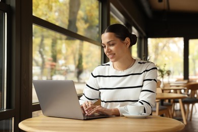 Photo of Woman working on laptop at table in cafe