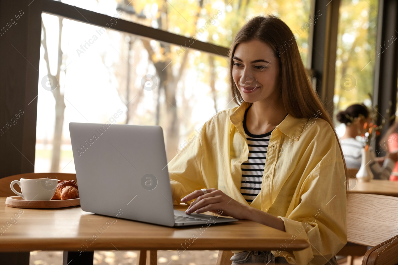 Photo of Woman working on laptop at table in cafe