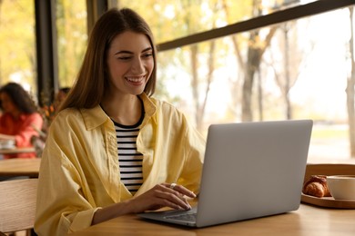 Photo of Woman working on laptop at table in cafe