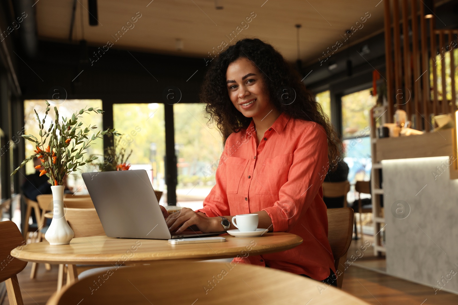 Photo of Woman working on laptop at table in cafe