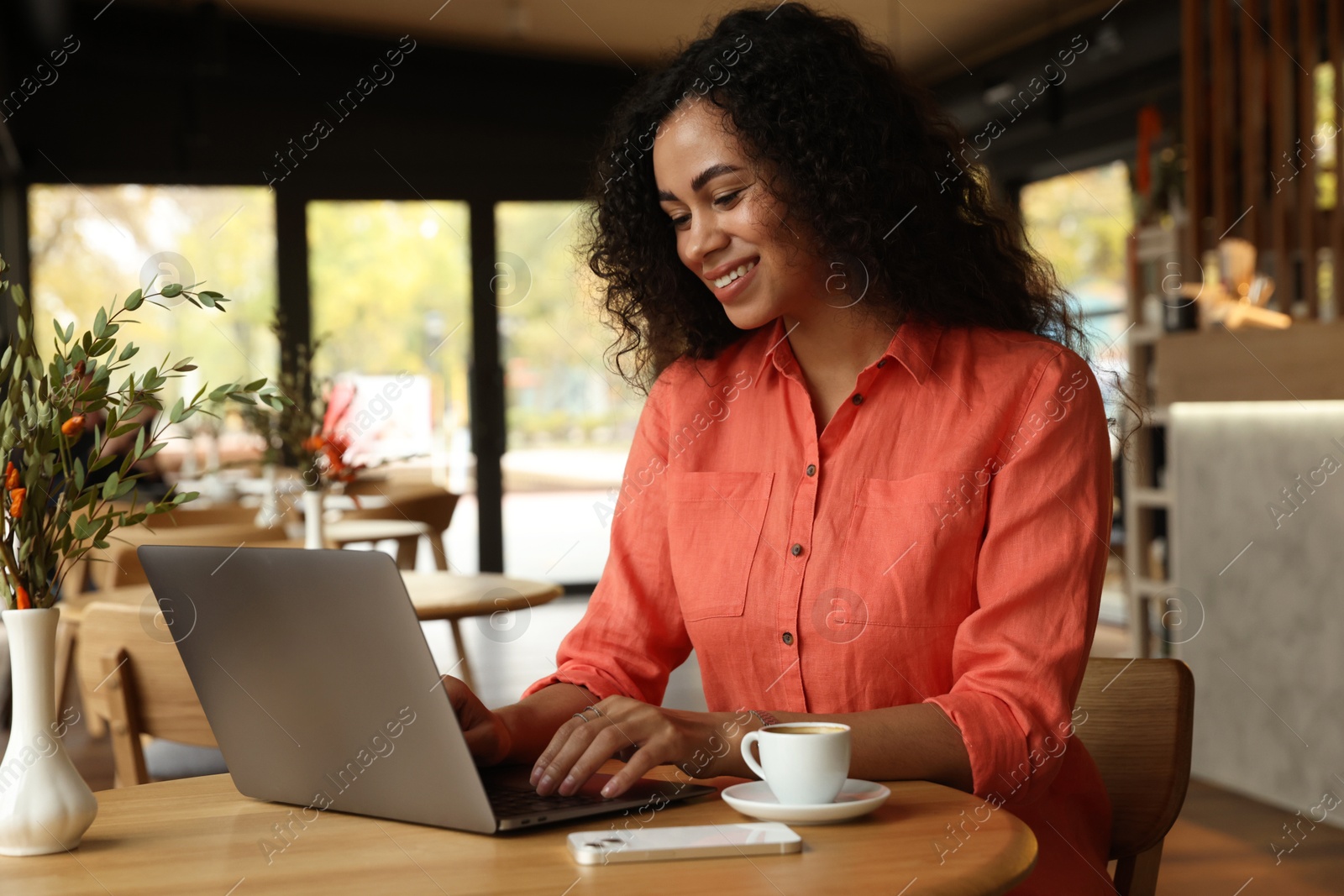 Photo of Woman working on laptop at table in cafe