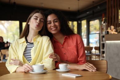 Photo of Happy women with coffee drinks at table in cafe