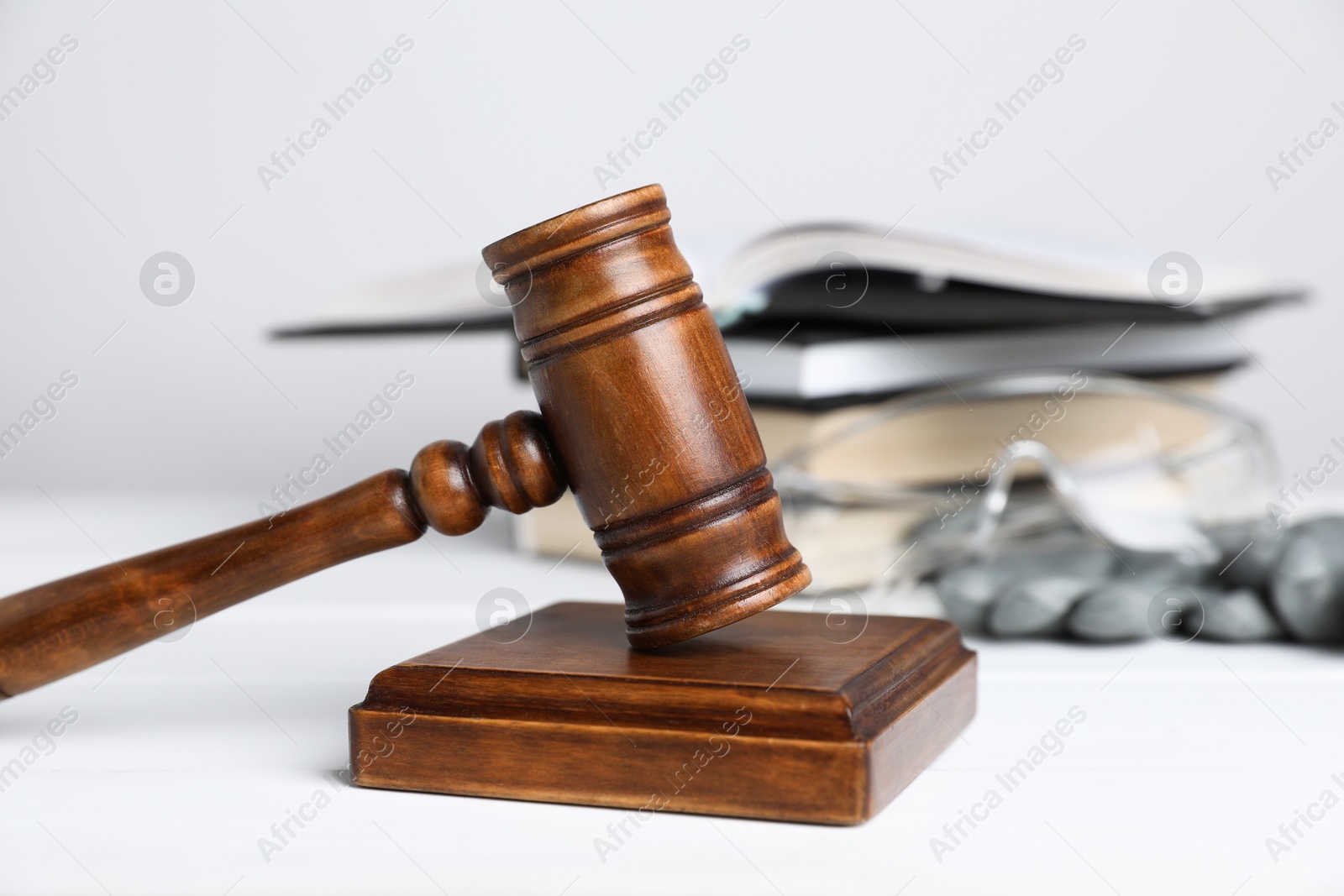 Photo of Accident at work concept. Gavel, books and construction worker's protective gear on white wooden table, selective focus