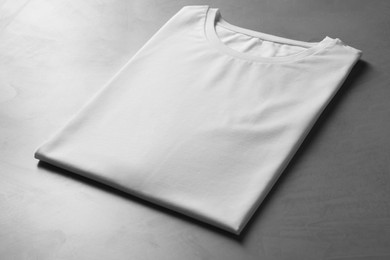 Photo of Blank white t-shirt on grey table, closeup. Mockup for design