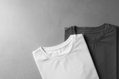 Photo of Different blank t-shirts on grey background, top view. Mockup for design