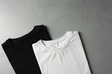 Photo of Different blank t-shirts on grey background, top view. Mockup for design