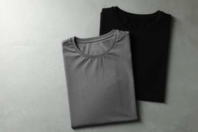 Photo of Different blank t-shirts on grey background, top view. Mockup for design