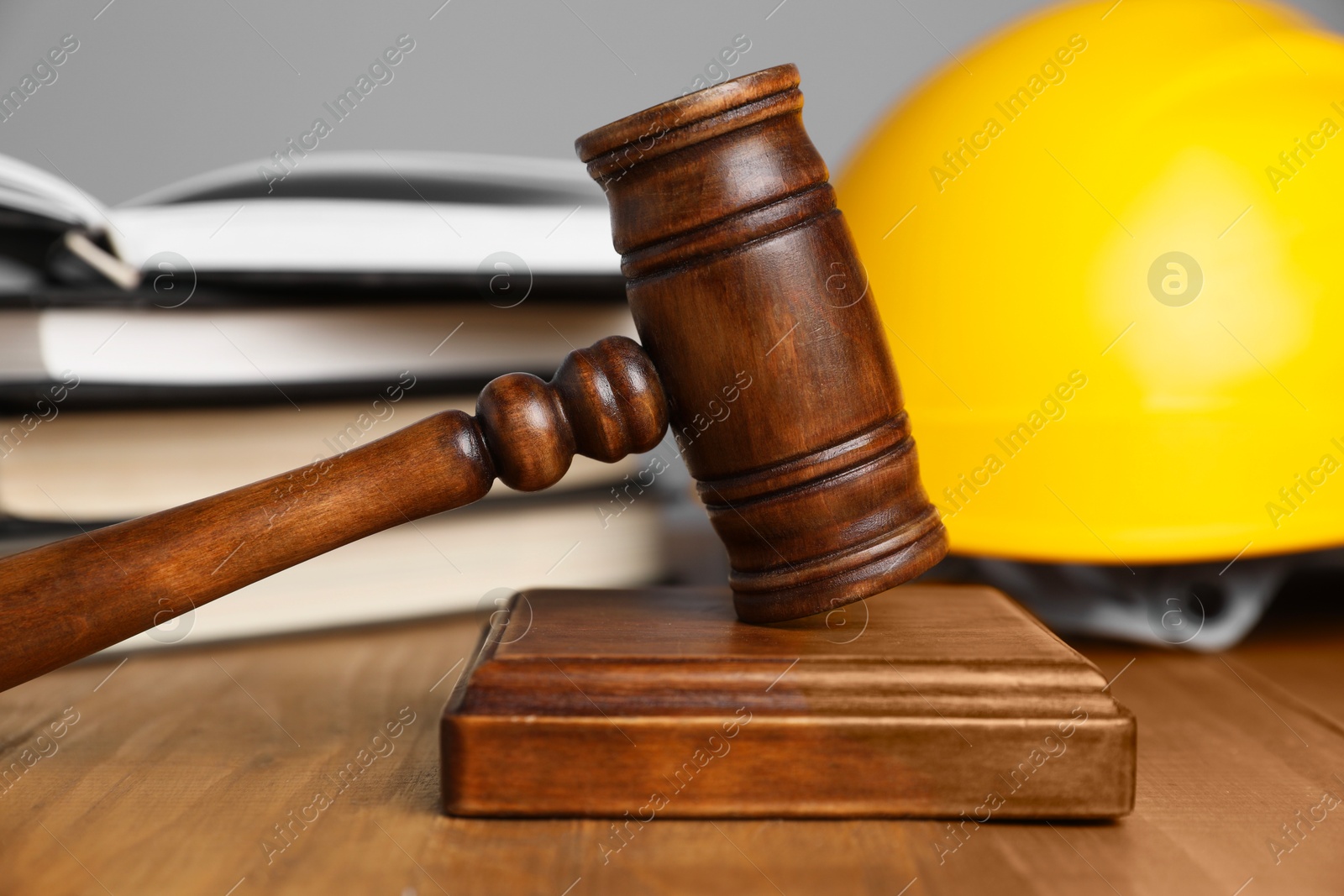 Photo of Accident at work concept. Gavel, books and construction worker's protective gear on wooden table, selective focus