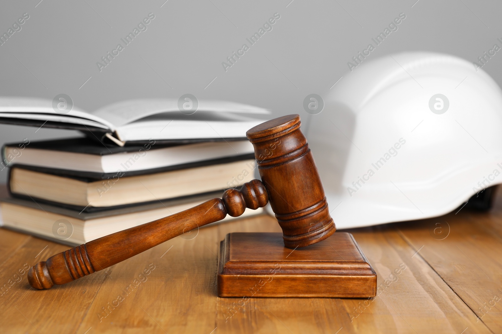 Photo of Accident at work concept. Gavel, books and construction worker's protective gear on wooden table, selective focus