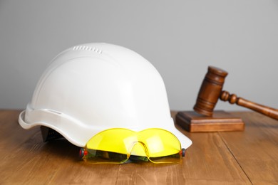 Photo of Accident at work concept. Gavel and construction worker's protective gear on wooden table, selective focus