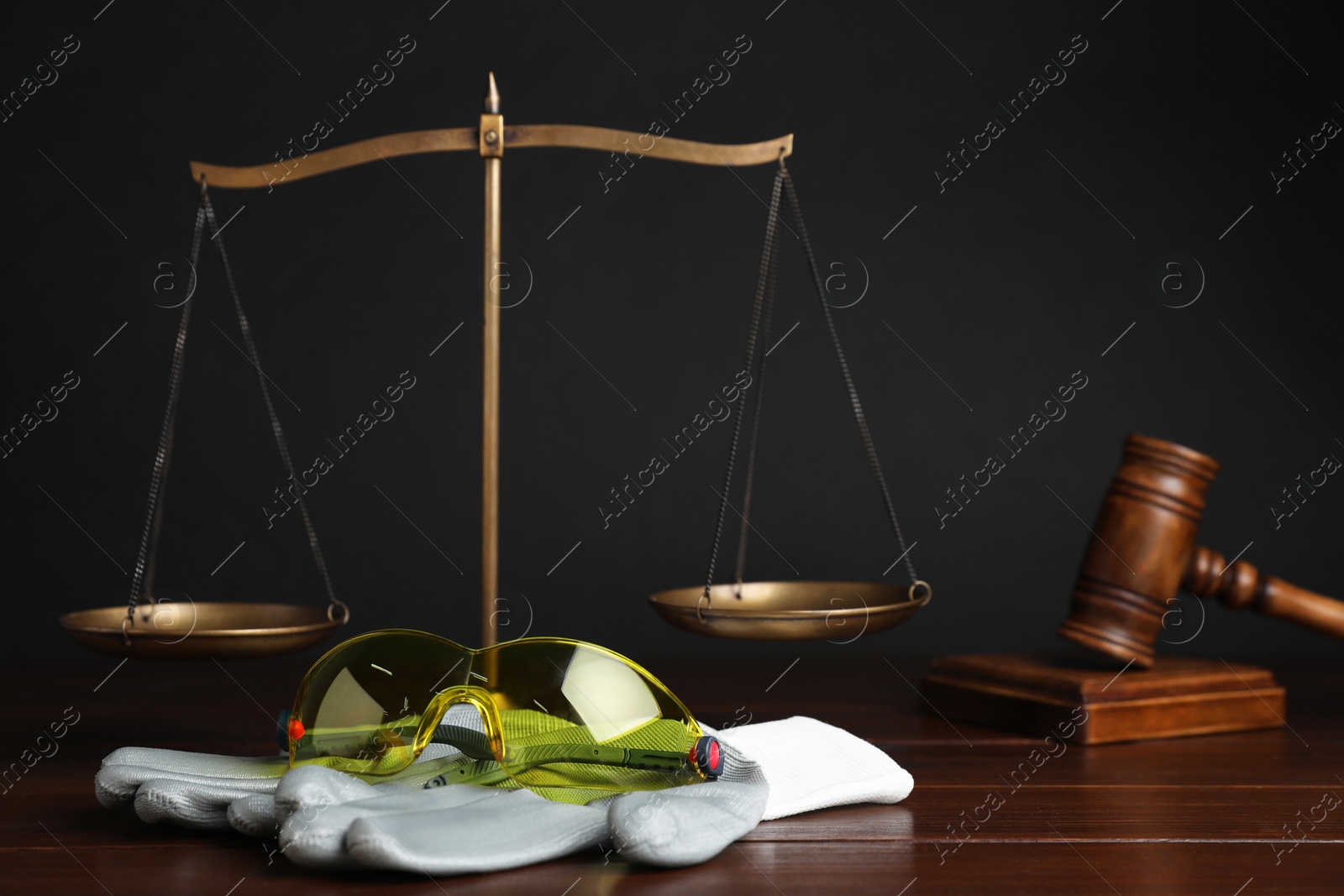 Photo of Accident at work concept. Gavel, scales and construction worker's protective gear on wooden table, selective focus