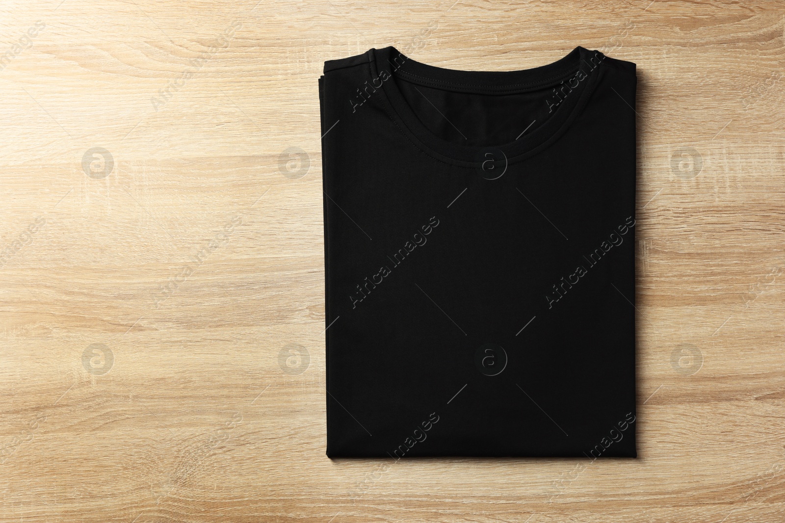 Photo of One blank t-shirt on wooden background, top view. Mockup for design