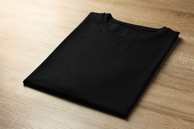 Photo of One blank t-shirt on wooden background, closeup. Mockup for design