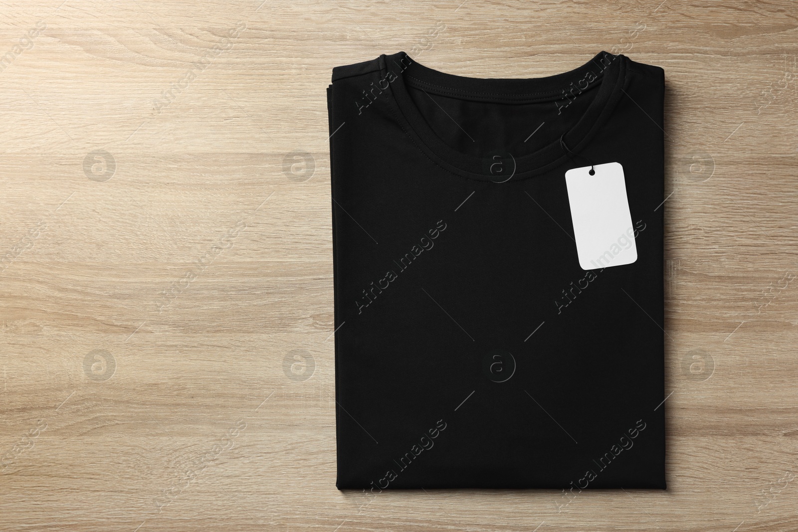 Photo of One blank t-shirt on wooden background, top view. Mockup for design