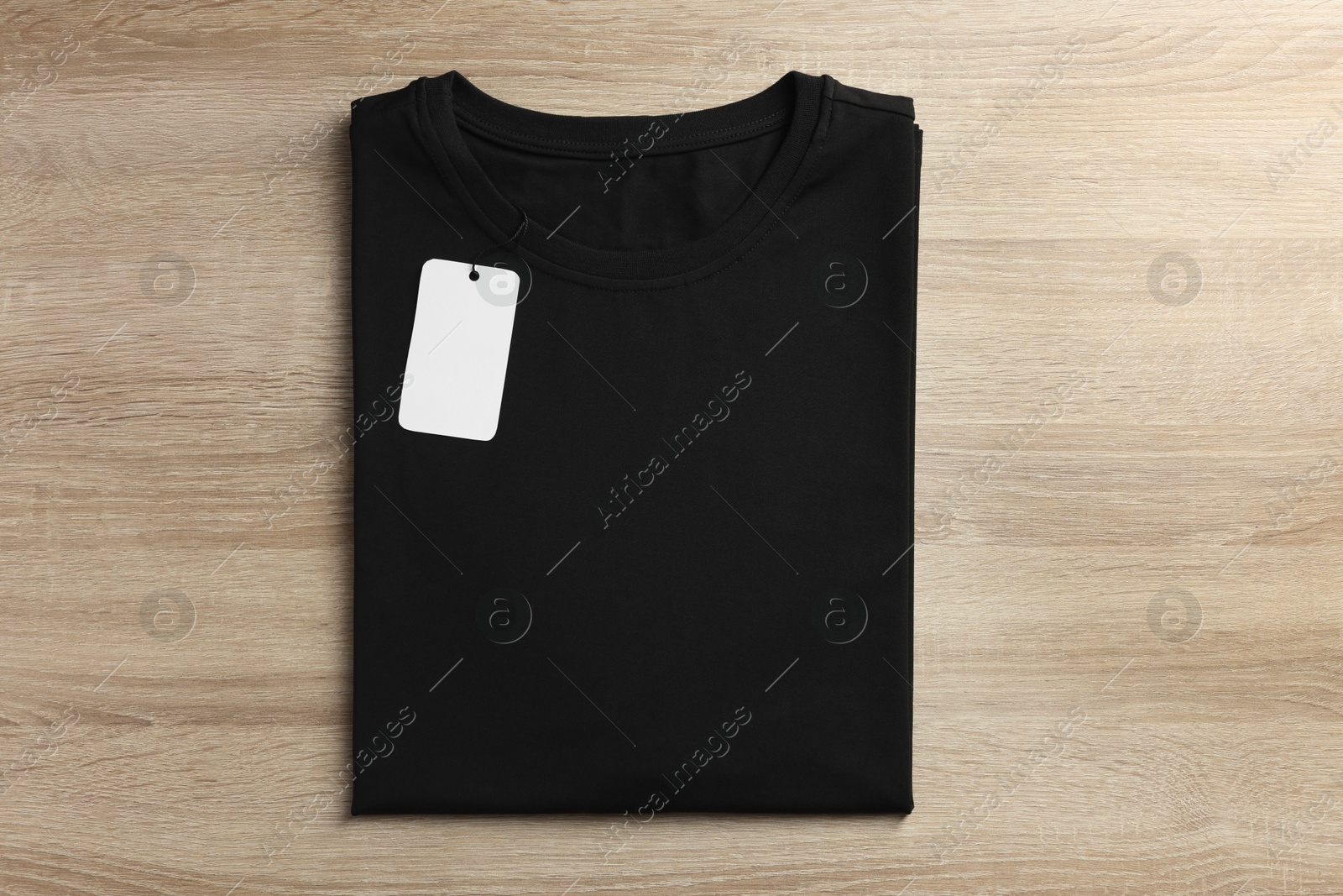 Photo of One blank t-shirt on wooden background, top view. Mockup for design