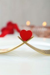 Photo of Romantic table setting for Valentine's day. Decorative heart between forks on white plate, closeup