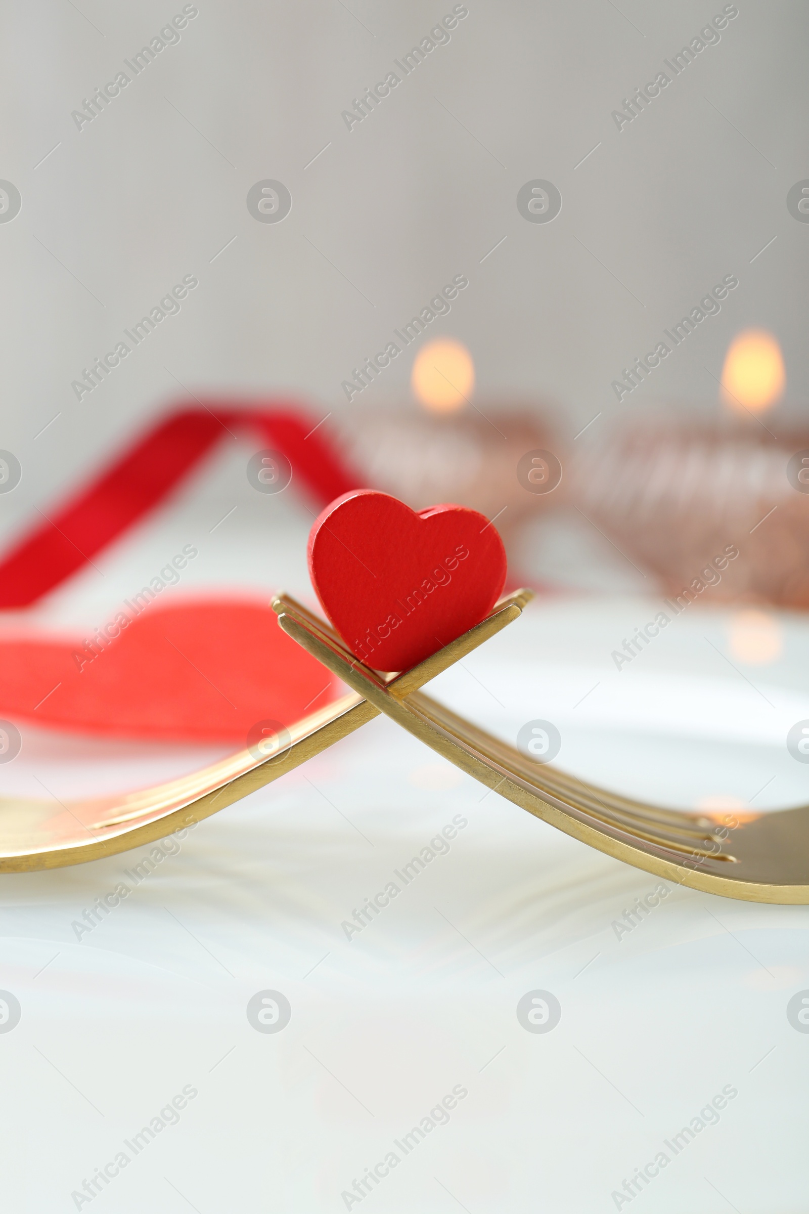 Photo of Romantic table setting for Valentine's day. Decorative heart between forks on white plate, closeup