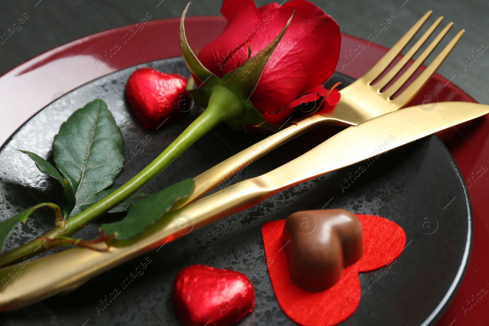 Photo of Romantic place setting with rose and plates on table, closeup. Valentine's day celebration