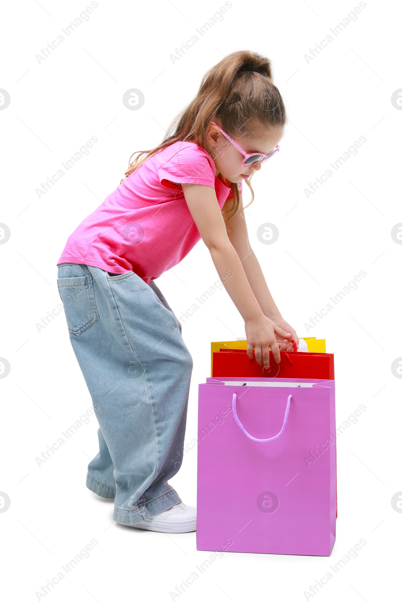 Photo of Cute little girl with shopping bags on white background