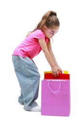 Cute little girl with shopping bags on white background