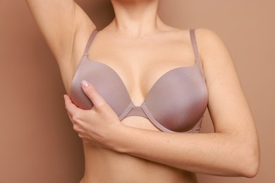 Photo of Woman wearing beautiful bra on beige background, closeup