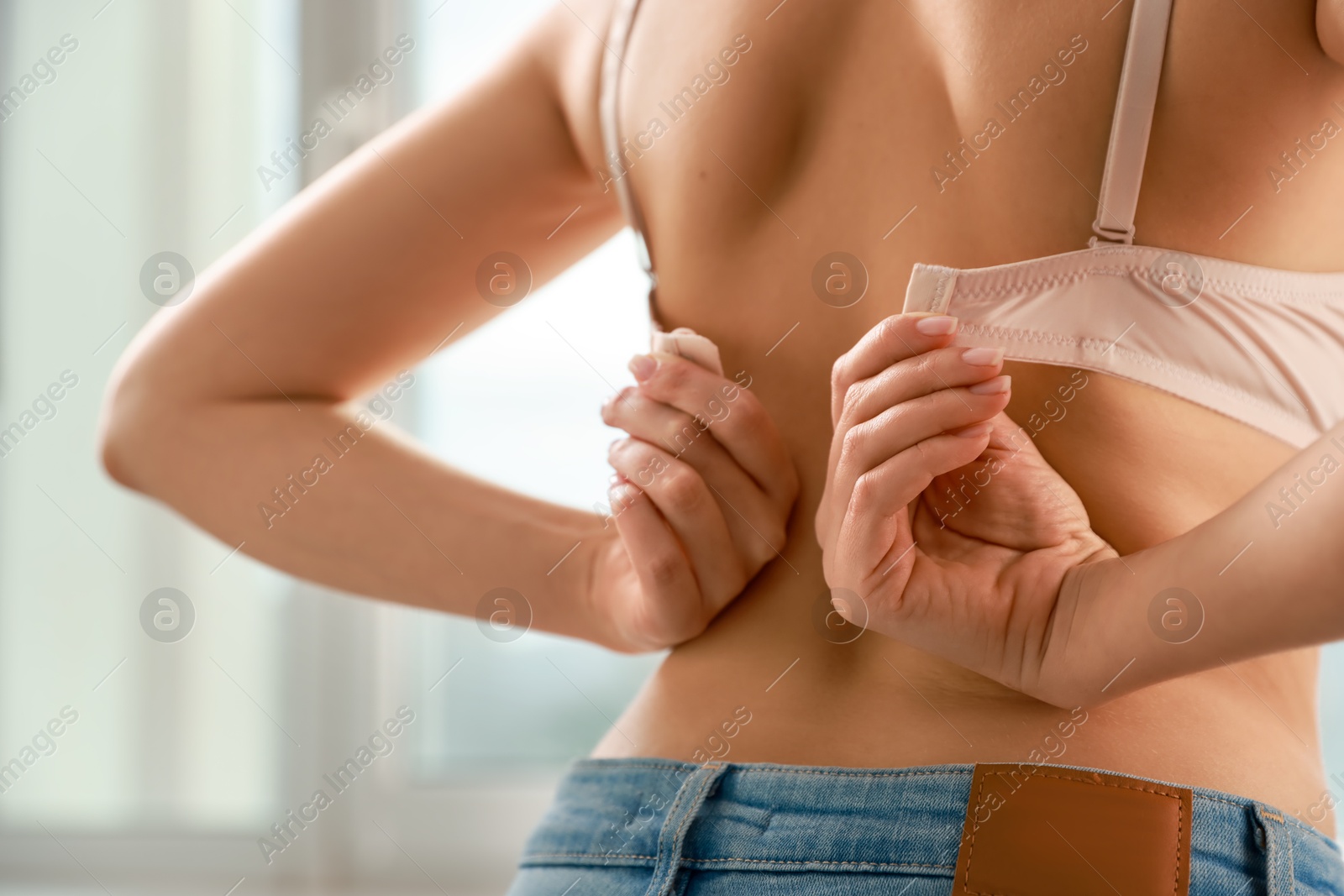 Photo of Woman putting on comfortable bra indoors, closeup