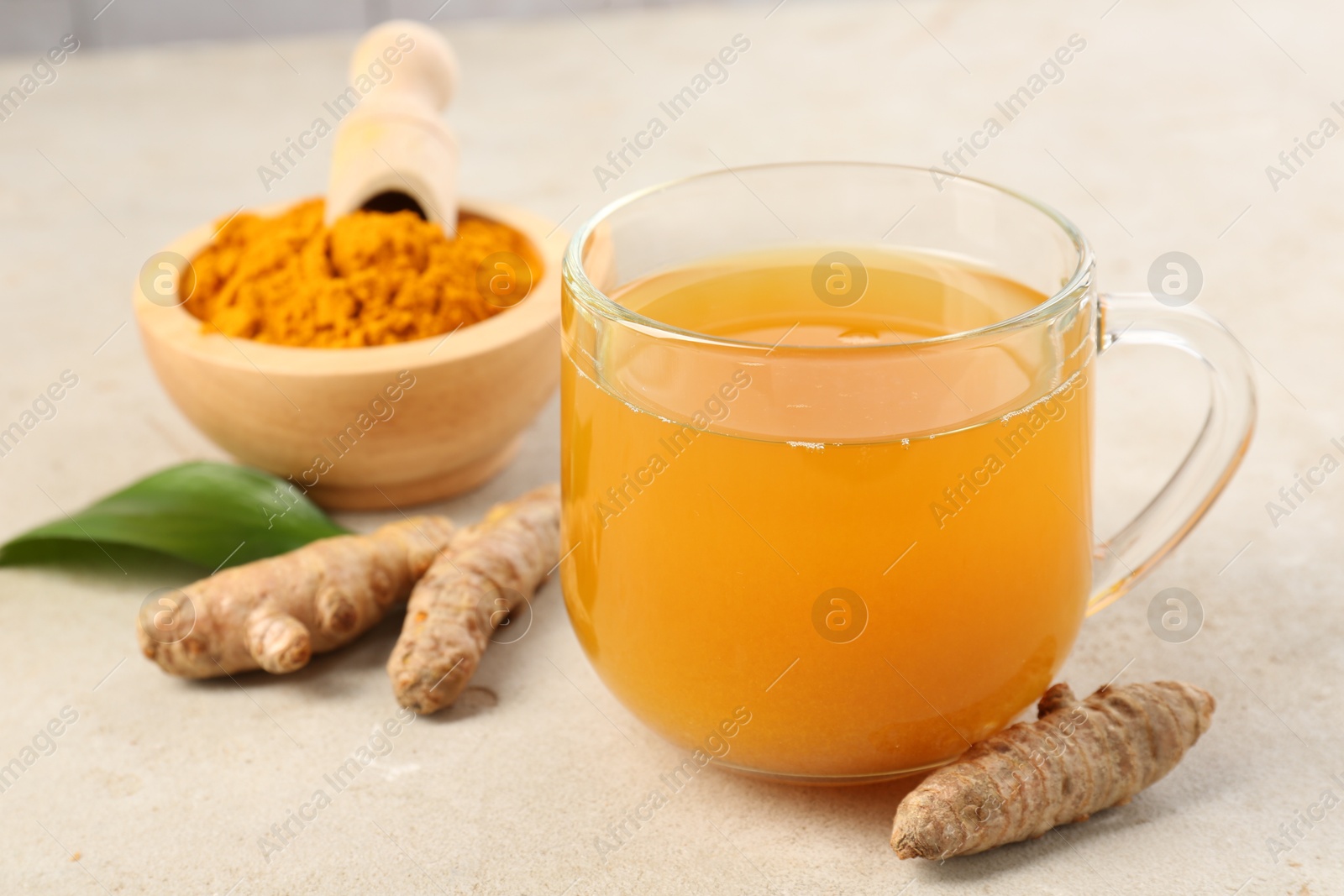 Photo of Aromatic turmeric tea, rhizomes and powder on white textured table, closeup