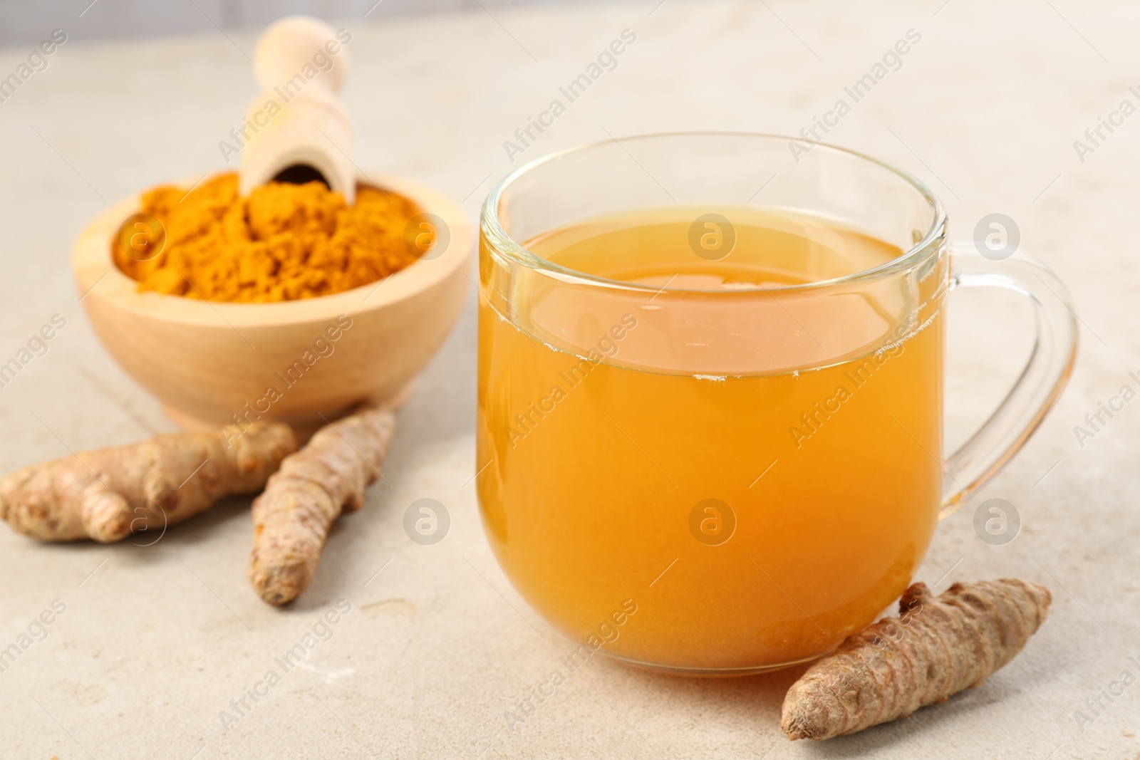 Photo of Aromatic turmeric tea, rhizomes and powder on white textured table, closeup