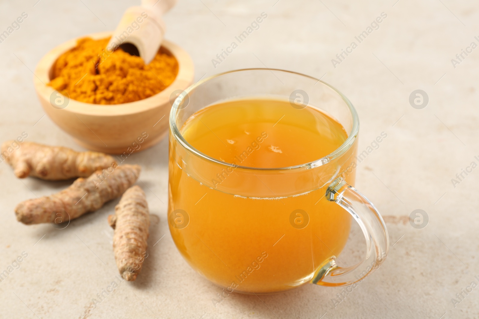 Photo of Aromatic turmeric tea, rhizomes and powder on white textured table, closeup