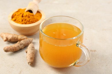 Photo of Aromatic turmeric tea, rhizomes and powder on white textured table, closeup