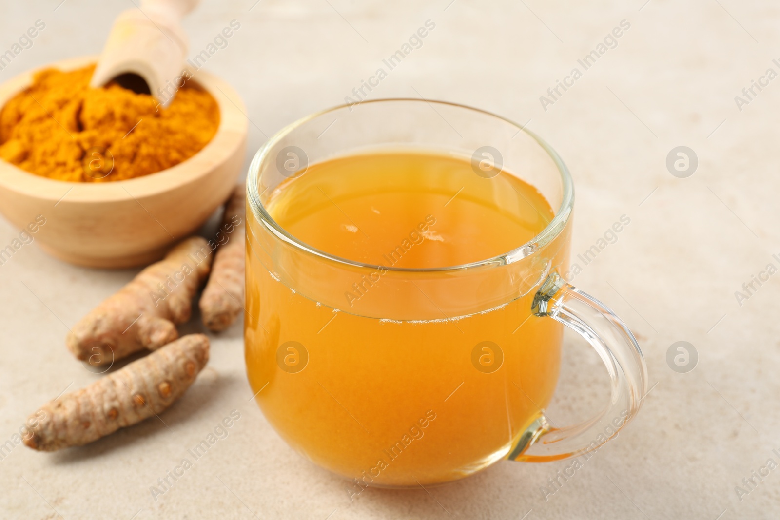 Photo of Aromatic turmeric tea, rhizomes and powder on white textured table, closeup