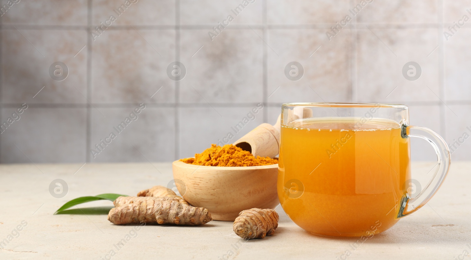 Photo of Aromatic turmeric tea, rhizomes and powder on white textured table. Space for text