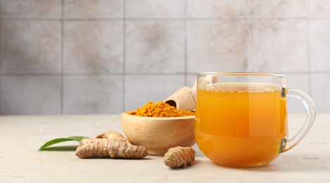 Photo of Aromatic turmeric tea, rhizomes and powder on white textured table. Space for text