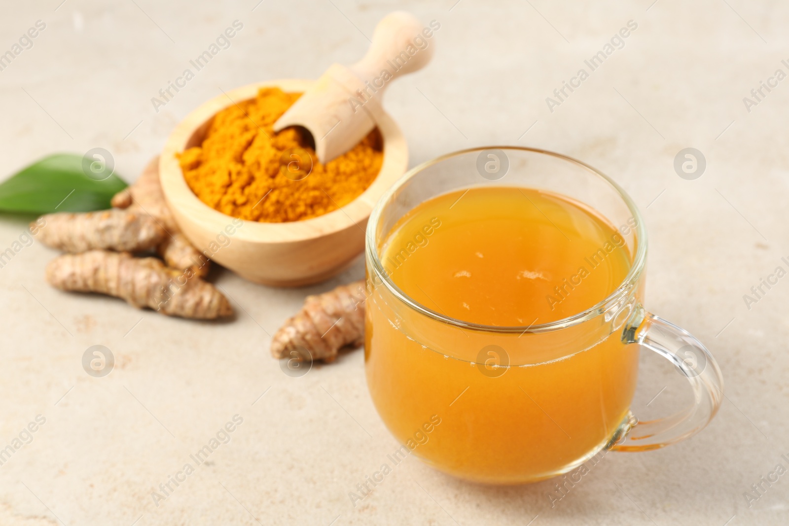 Photo of Aromatic turmeric tea, rhizomes and powder on white textured table, closeup