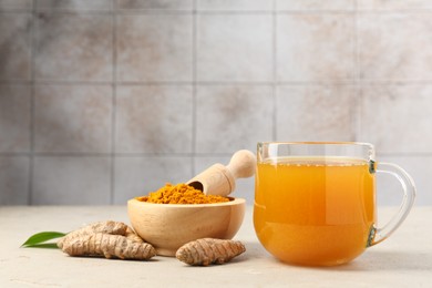 Photo of Aromatic turmeric tea, rhizomes and powder on white textured table