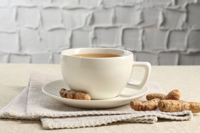 Photo of Aromatic turmeric tea and rhizomes on white textured table