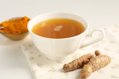 Photo of Aromatic turmeric tea, powder and rhizomes on white table, closeup