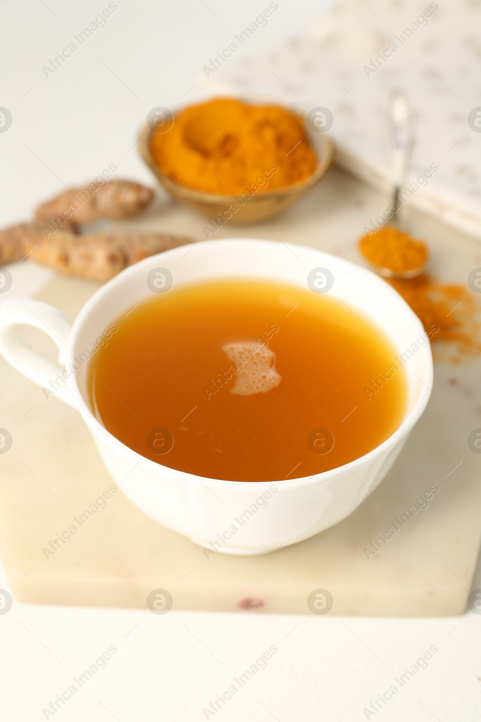 Photo of Aromatic turmeric tea, powder and rhizomes on white table, closeup