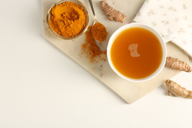 Photo of Aromatic turmeric tea, powder and rhizomes on white table, flat lay. Space for text