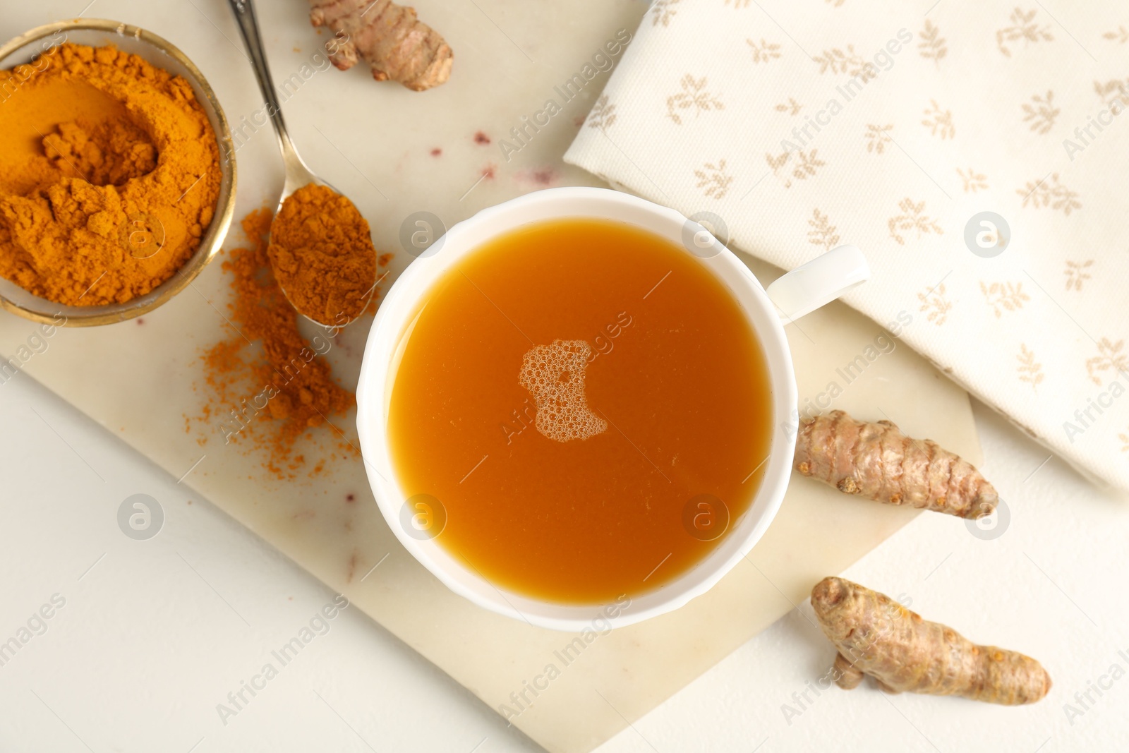 Photo of Aromatic turmeric tea, powder and rhizomes on white table, flat lay