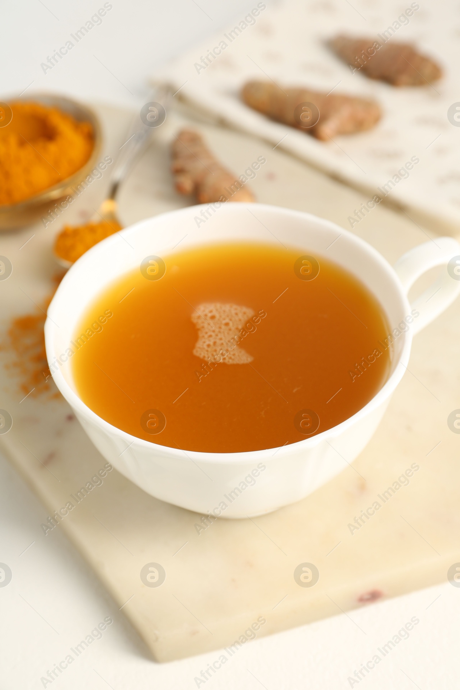 Photo of Aromatic turmeric tea, powder and rhizomes on white table, closeup