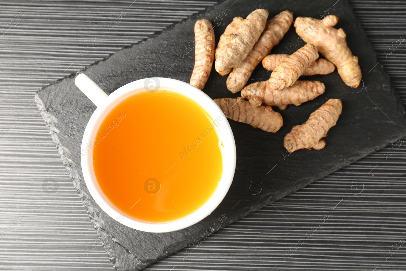 Photo of Aromatic turmeric tea and rhizomes on black table, top view