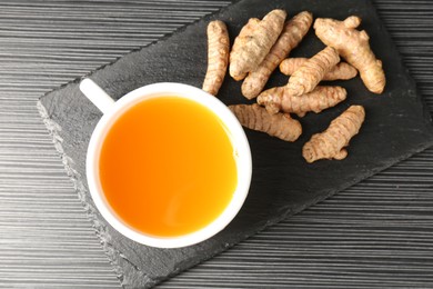 Photo of Aromatic turmeric tea and rhizomes on black table, top view