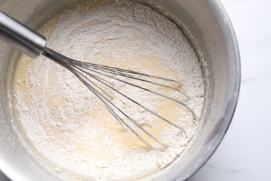 Photo of Whisk and bowl of dough on white table, top view